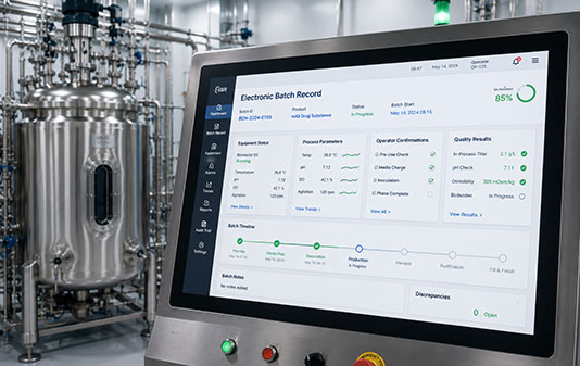 Electronic Batch Record interface beside a bioreactor in a GMP biopharmaceutical manufacturing facility.